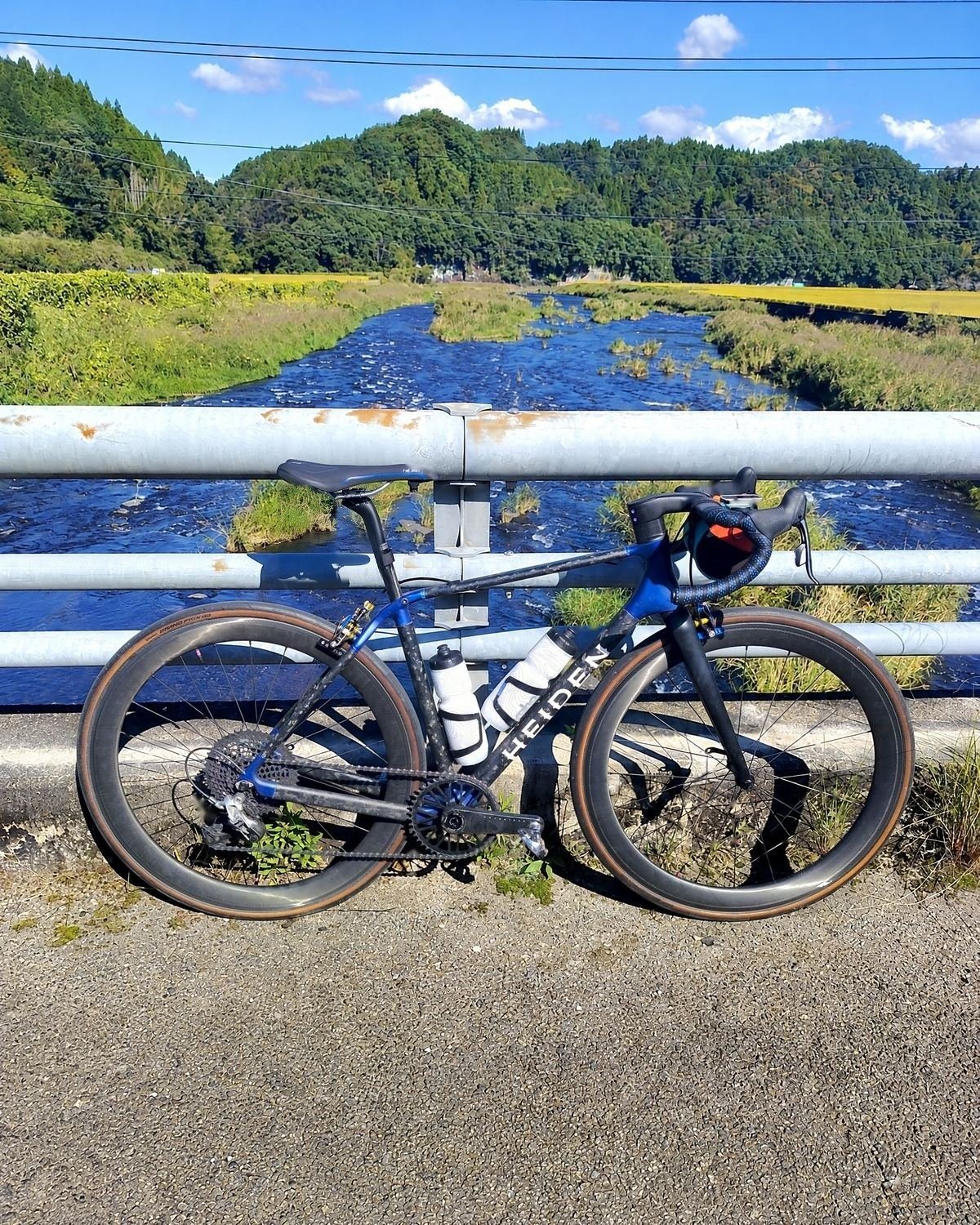 Heiden bike on a bridge over a clear river between rice fields